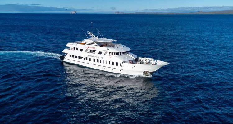 White expedition yacht cruising through deep blue open waters under a clear sky.