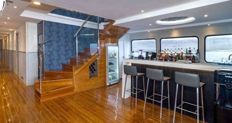 Interior moderno de yate con suelos de madera pulida, bar y escalera con vista al mar.