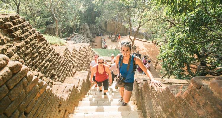 Groep reizigers die steile oude stenen trappen beklimt door jungle ruïnes.