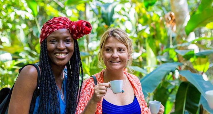 Twee vrouwen die genieten van kopjes thee in een weelderige tropische tuin.