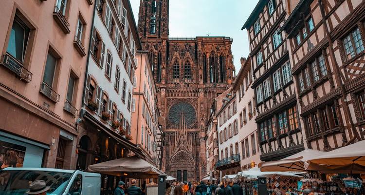 Catedral gótica vista a través de una calle estrecha con gente y tiendas.