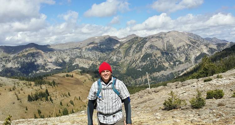 Personne posant avec un paysage montagneux.