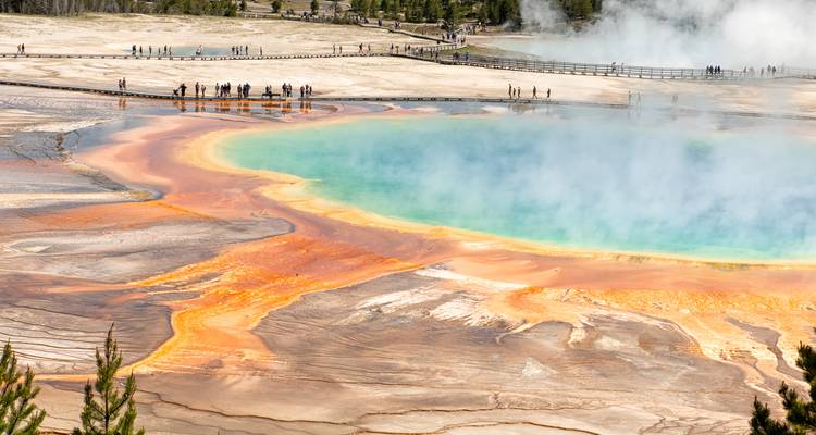 Source prismatique colorée émettant de la vapeur au milieu du paysage géothermique de Yellowstone.