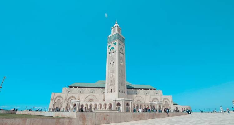 Grande mosquée ornée avec une tour et un large espace ouvert devant.