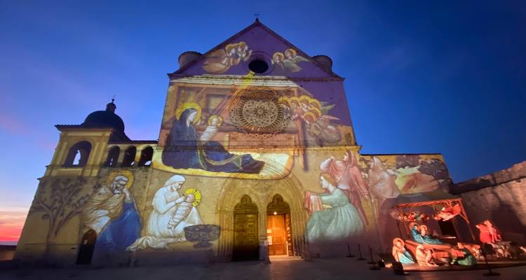 Façade de cathédrale illuminée avec des images religieuses projetées sur le devant.
