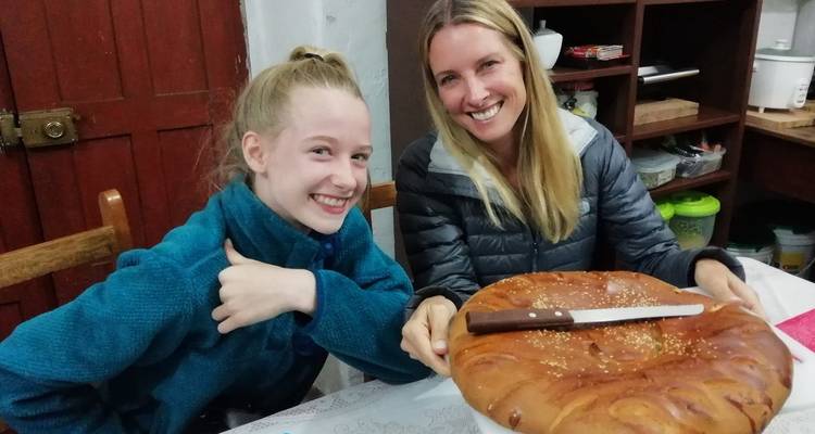 Twee vrouwen die glimlachen met een groot brood op de tafel.