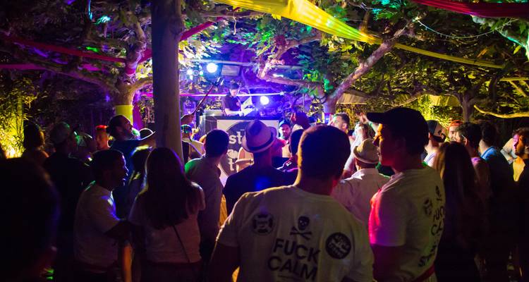 Fête nocturne avec lumières colorées et DJ.