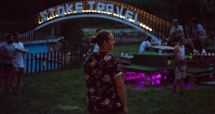People relaxing at night in a grassy area with a decorated archway.