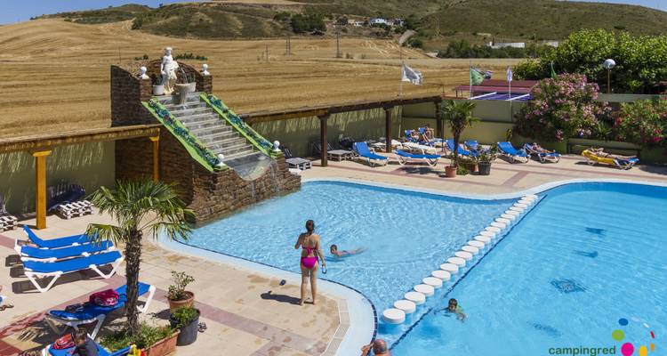 Swimming pool with a waterslide and lounge chairs in a rural setting
