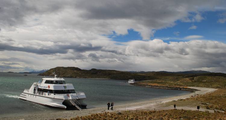 Passagiersboot aangemeerd bij een afgelegen strand, bewolkte lucht.