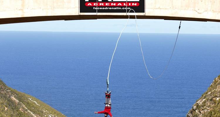 Salto en bungee desde un puente con vista al océano.