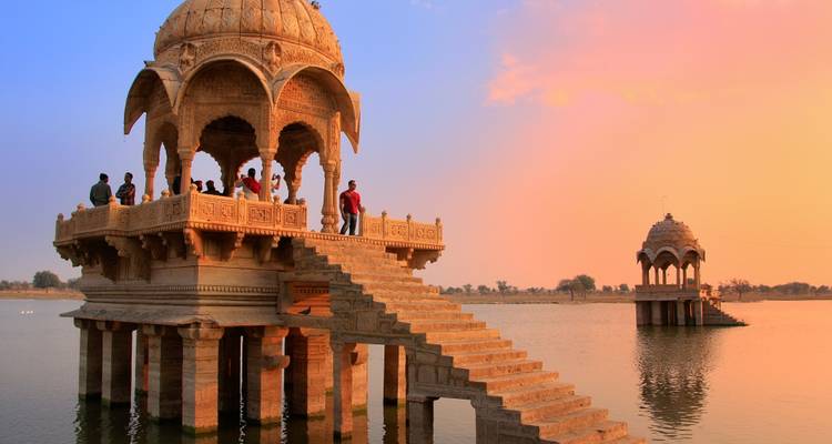 Pavillon élégant sur un lac au coucher du soleil avec des gens qui admirent la vue.