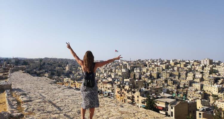 Femme profitant d'une vue panoramique sur une ville avec les bras levés.