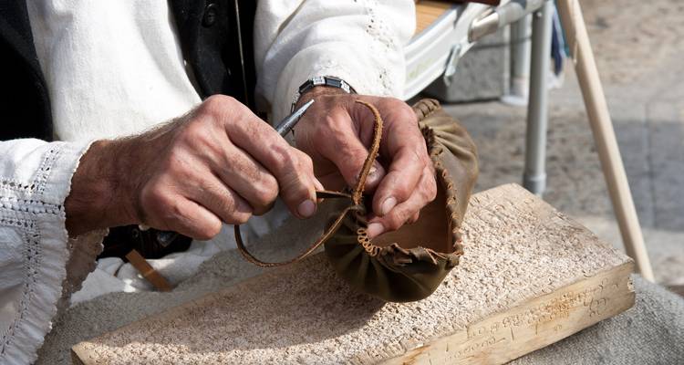 Close-up of hands stitching leather footwear using traditional techniques on a workbench
