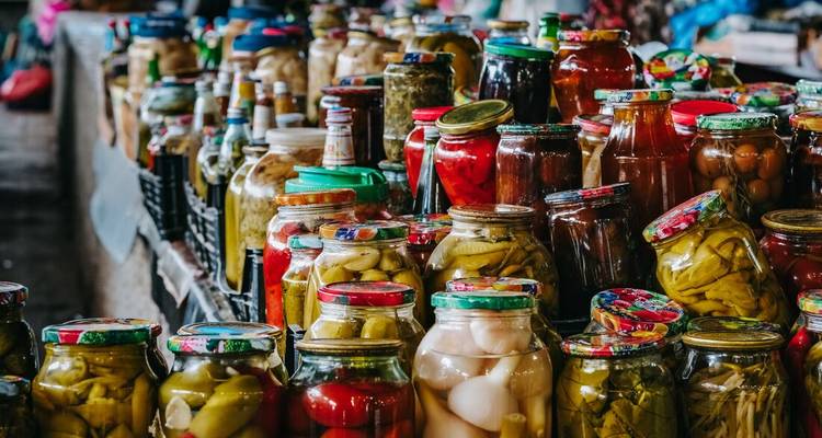 Frascos variados de verduras encurtidas cuidadosamente apilados en un mostrador de mercado georgiano