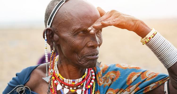 Anciana masai protegiéndose los ojos del sol con un atuendo tradicional.