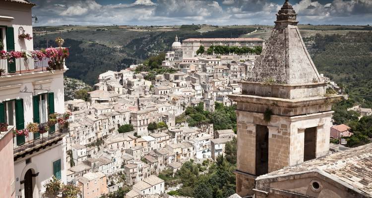 Panorama depuis les hauteurs des maisons en pierre de Ragusa Ibla et de ses églises baroques sous des nuages dramatiques.