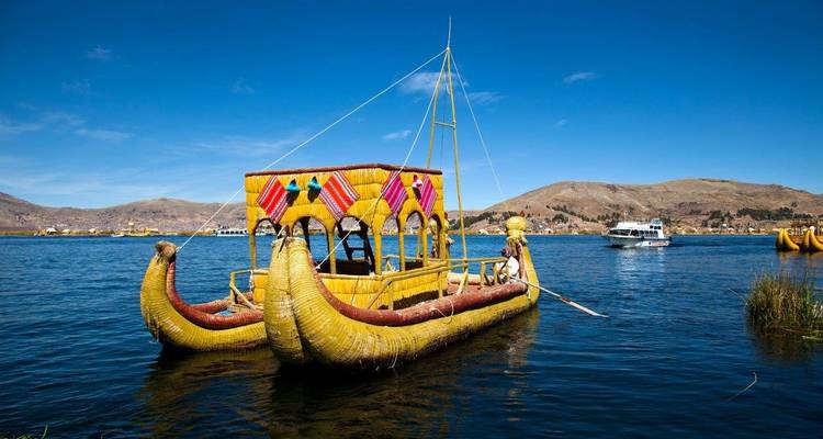 Kleurrijke rieten boot op het Titicacameer met bergen op de achtergrond.