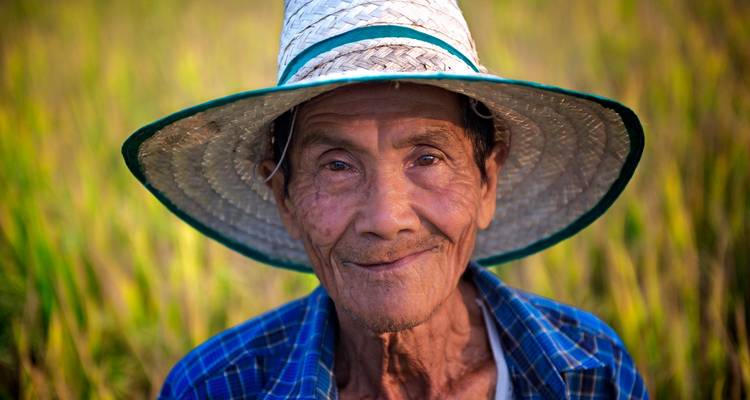 Homme âgé dans un champ portant un chapeau de paille.