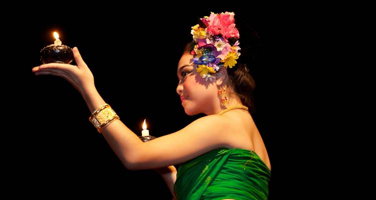 Femme en tenue traditionnelle tenant des bougies.