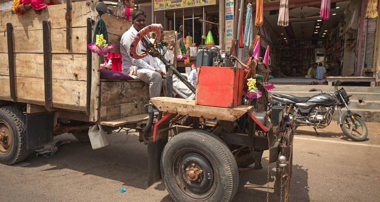 Hombre conduce carreta de madera rústica decorada por calle de mercado concurrida