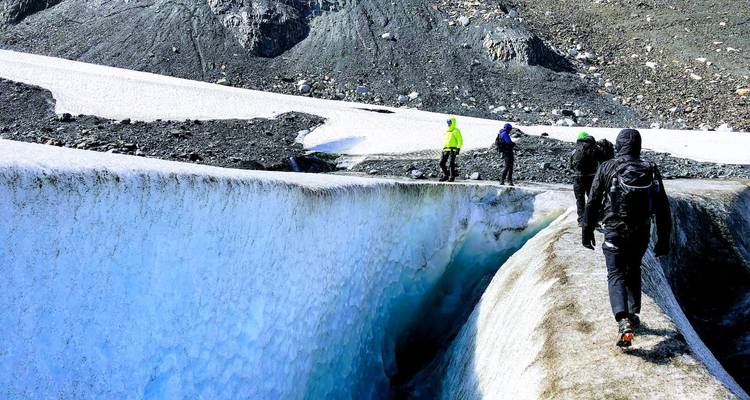 Wandelaars die langs een besneeuwde pad lopen in een ruig landschap.