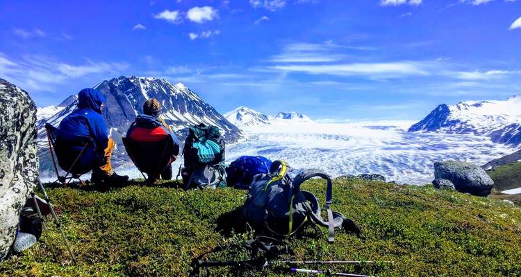 Wandelaars zittend op gras met een gletsjer op de achtergrond.