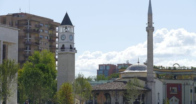 Clock tower and mosque in a city square.