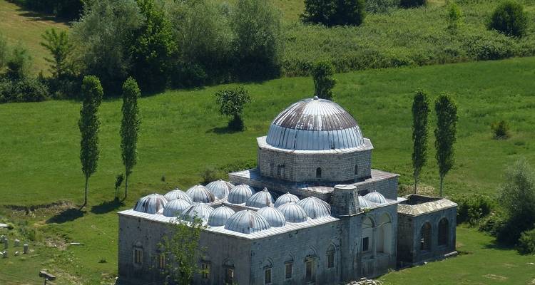 Historic dome-roofed building in a grassy field.