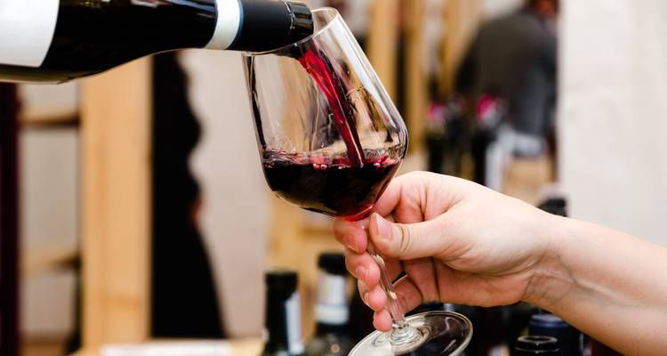 Sommelier vertiendo vino tinto de la botella en una copa de degustación durante el evento de bodega