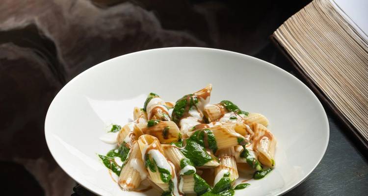 Gourmet-Nudelgericht mit grüner Kräutersauce garniert und elegant in einer weißen Schüssel angerichtet