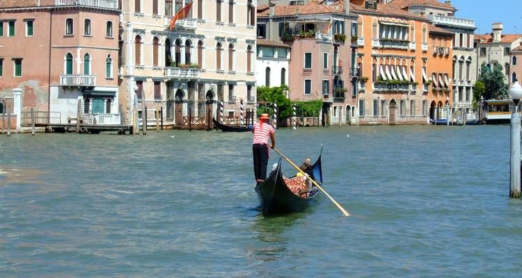 Gondolier ramant une gondole avec des passagers le long d'un canal.
