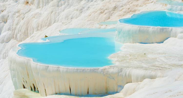 Piscinas termales turquesas que descienden en cascada sobre terrazas de travertino blanco