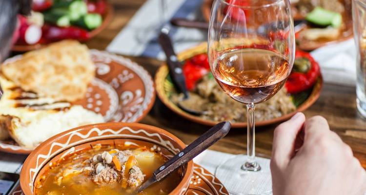 Primer plano de comida local en cuencos de barro con una copa de vino.