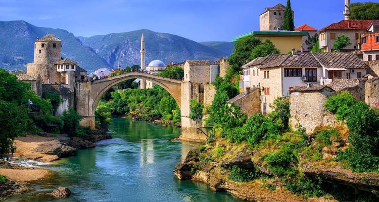 Pont de pierre historique traversant une rivière avec des bâtiments de chaque côté.