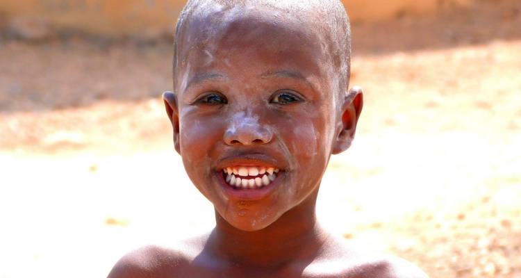 Niño sonriente con la cara pintada de sustancia blanca.