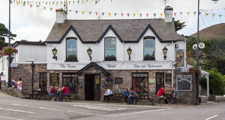 Pub de village irlandais traditionnel avec des bancs extérieurs où les habitants et les visiteurs s'assoient et bavardent.