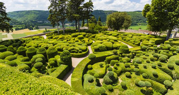 Des jardins de topiaire complexes aux motifs de labyrinthe dominant la campagne vallonnée.