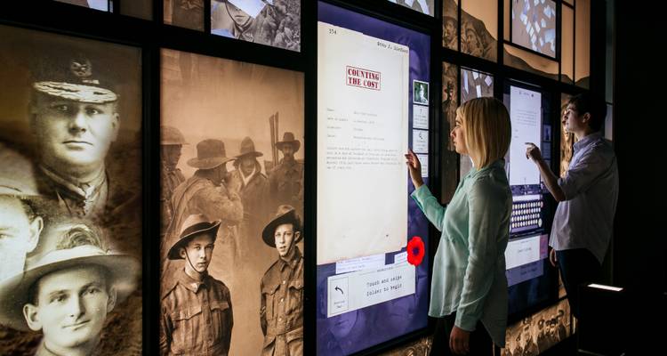 Visitantes interactuando con las exhibiciones digitales de guerra en el Centro Nacional ANZAC.