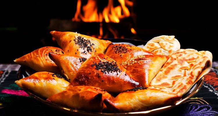 Plato de pasteles tradicionales con un fuego de fondo.