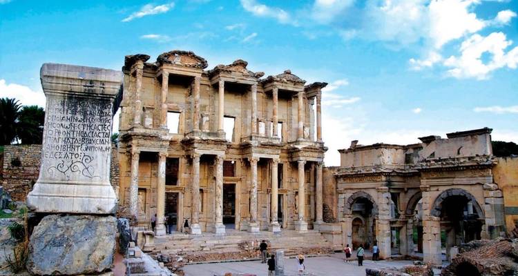 Ancient library ruins with monumental architecture and visitors exploring.