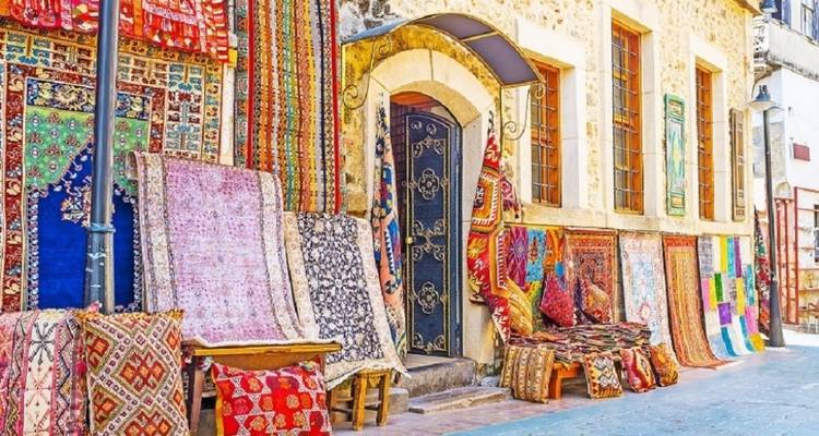 Étalage coloré de tapis traditionnels suspendus à l'extérieur d'une boutique.