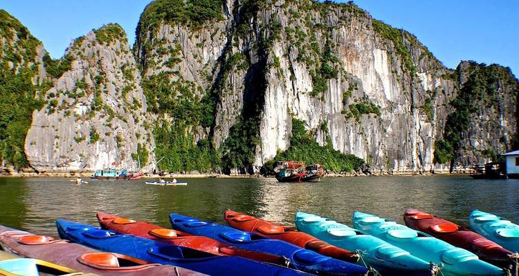 Kleurrijke kajaks opgesteld op het water met kalkstenen kliffen.
