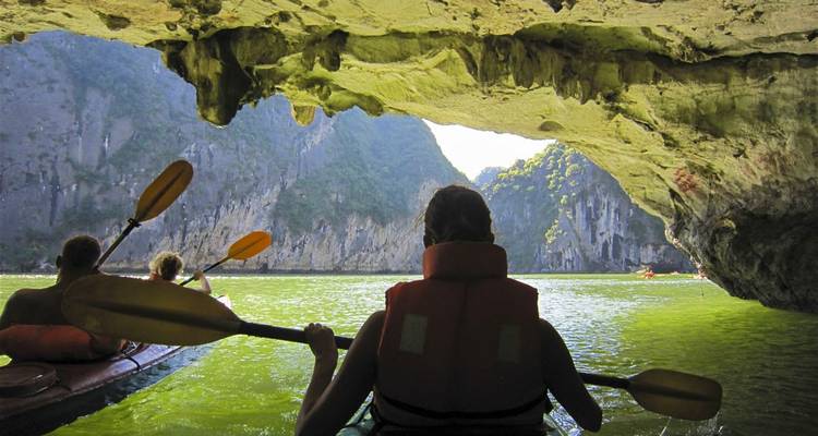 Mensen kajakken door een grot in Halong Bay, Vietnam.