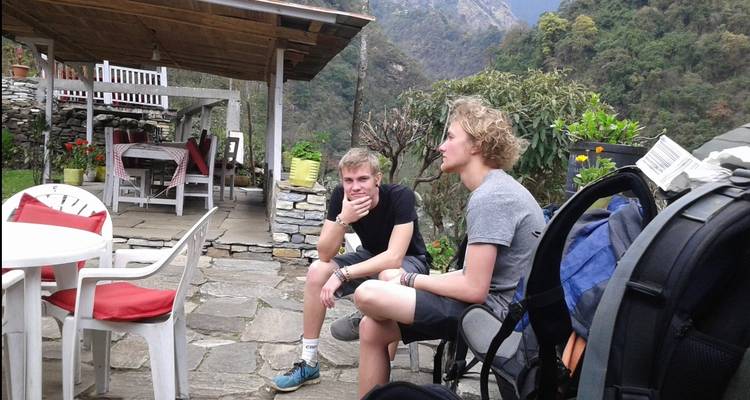 Twee wandelaars rusten uit op een terrasje in de bergen.