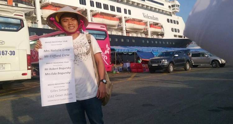 Person holding a welcome sign in front of a large cruise ship.