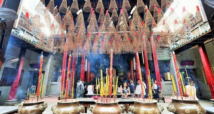 Interior of a temple with large incense coils hanging from the ceiling.