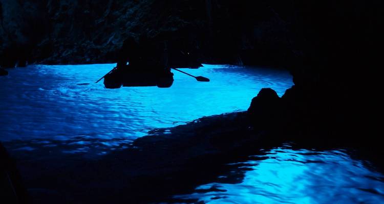 Cueva misteriosa iluminada con agua azul.