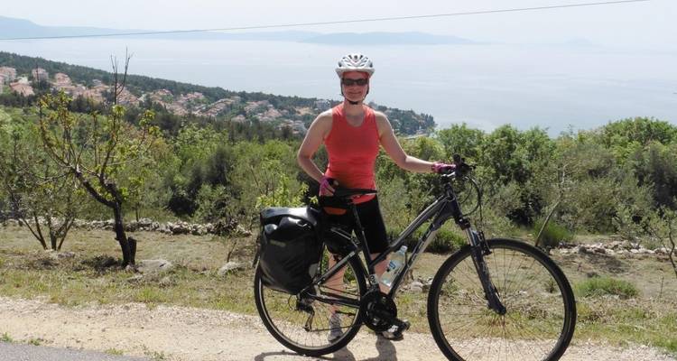 Cyclist posing with a bicycle against a scenic view.