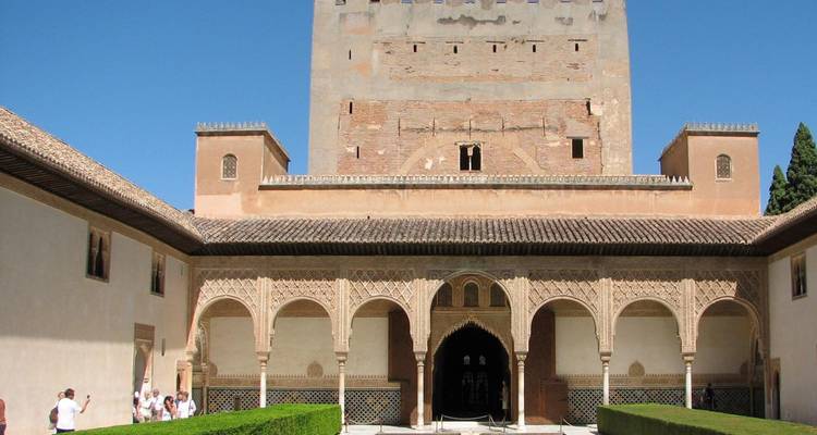 Cour mauresque avec des arches ornées et des haies taillées à l'intérieur du complexe de l'Alhambra par une journée ensoleillée.
